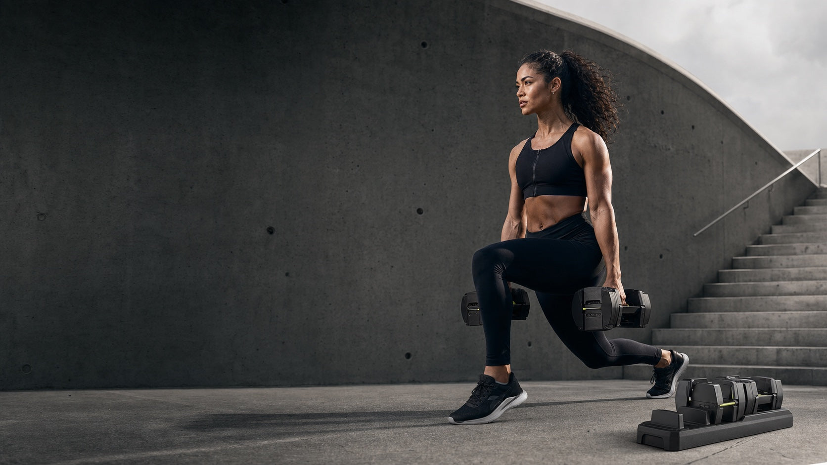 Athlete training with compact adjustable dumbbells
